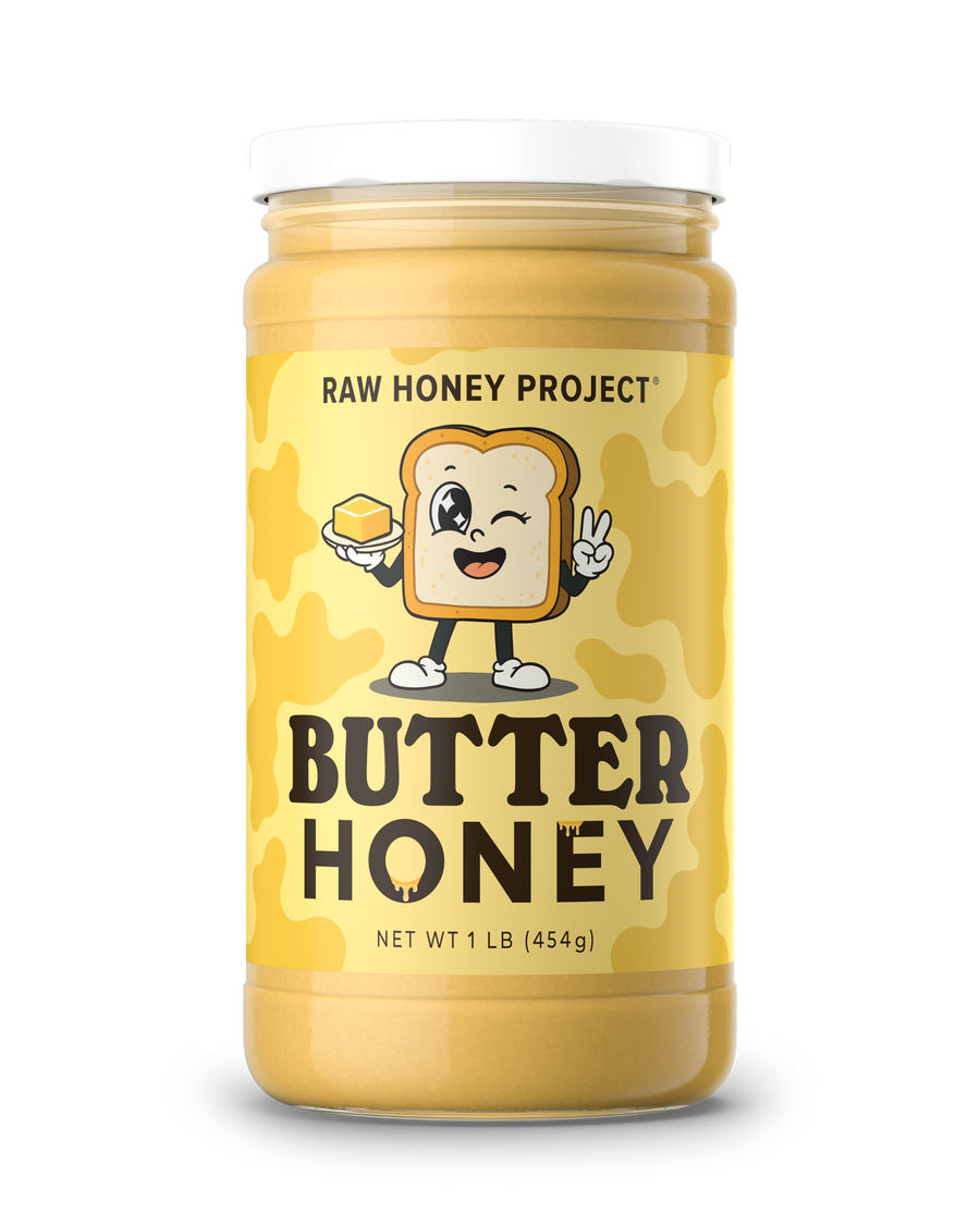 A jar of Raw Honey Project Butter Honey with a white lid and a yellow label featuring a cartoon slice of toast holding a pat of butter, set against a plain white background.
